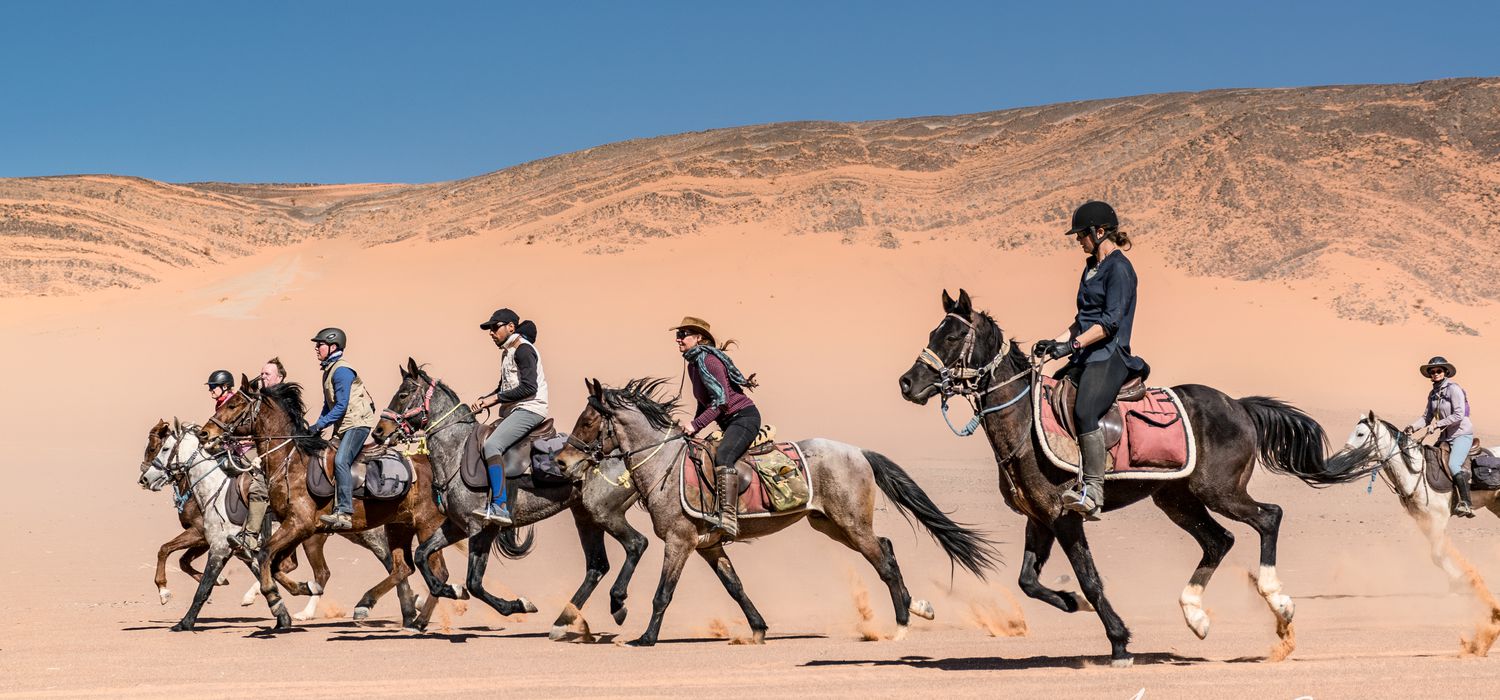 Group horseback riding expedition through the Moroccan desert